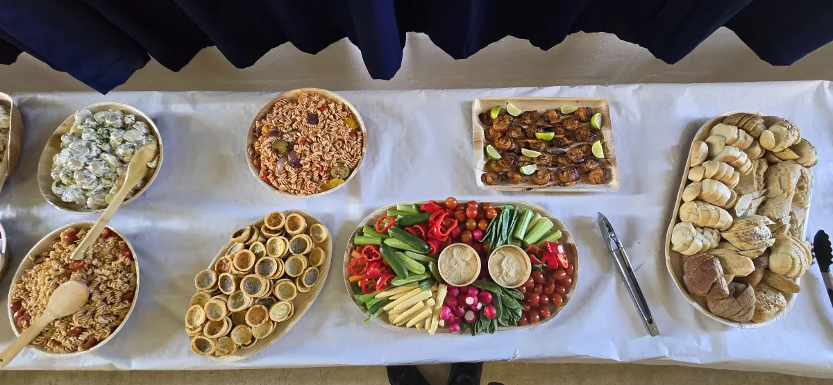 Boardroom table laid with catering boxes, salads and new potatoes for a corporate lunch