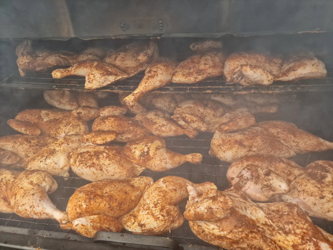 Rows of roasted chicken halves in catering trays at an event